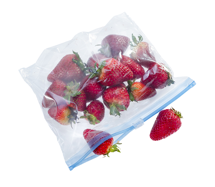 Strawberry in clear plastic bag isolated on white background .